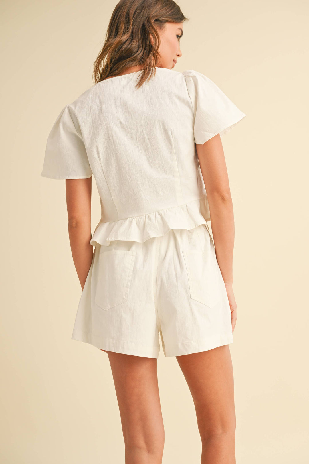 Woman wearing white shorts with back pocket 