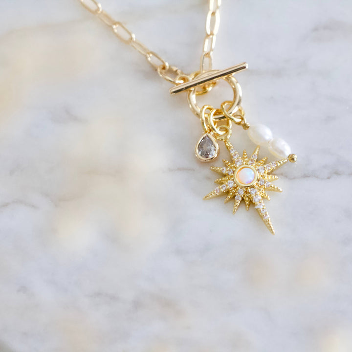 Gold necklace with star-shaped pendant on a marble background