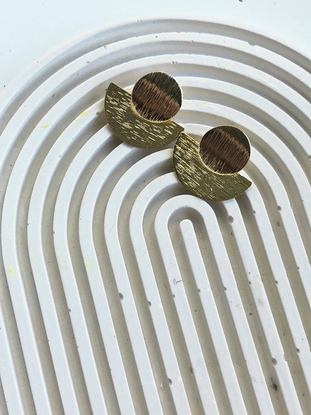 Pair of half moon gold statement earrings on a white background