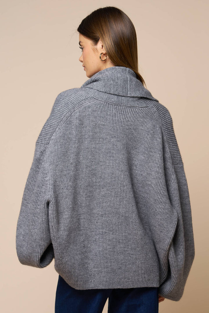 Woman wearing a gray knitted oversized cardigan on a beige background