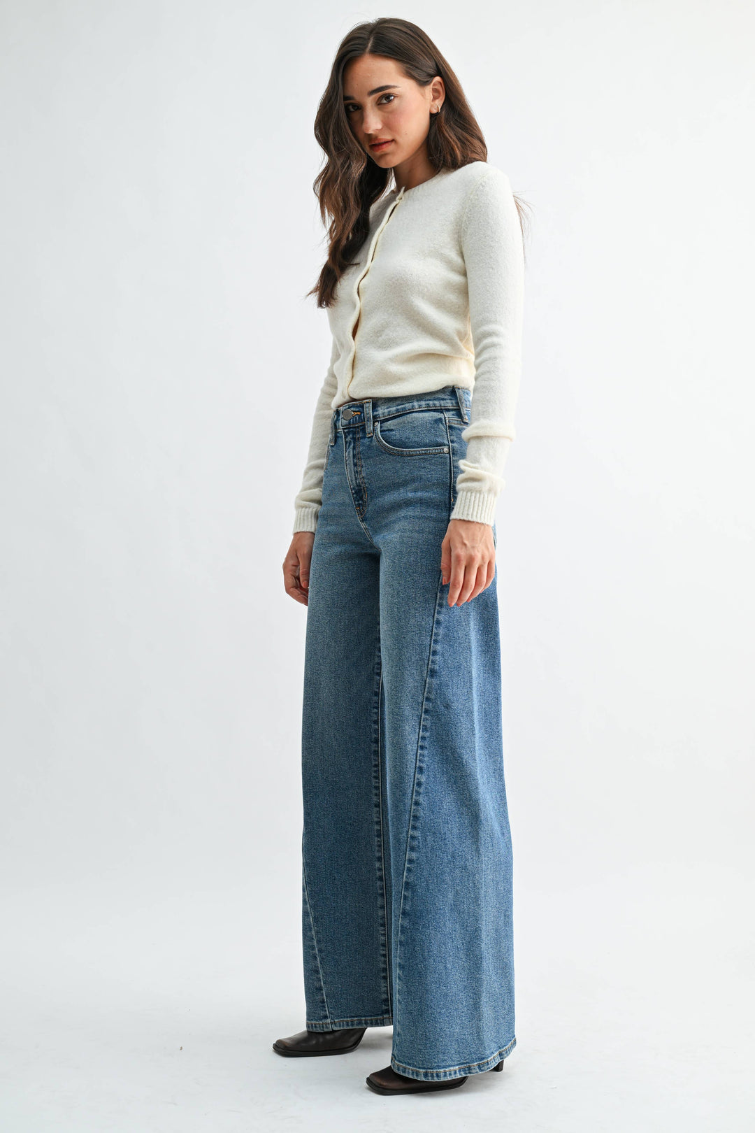 Woman wearing blue wide leg jeans on a white background