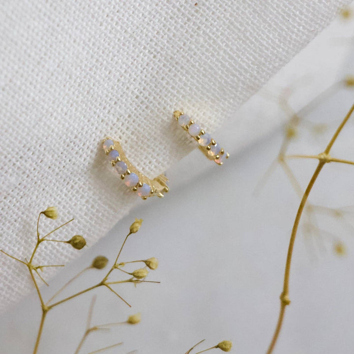 Gold earrings with opalite stones on a white fabric background