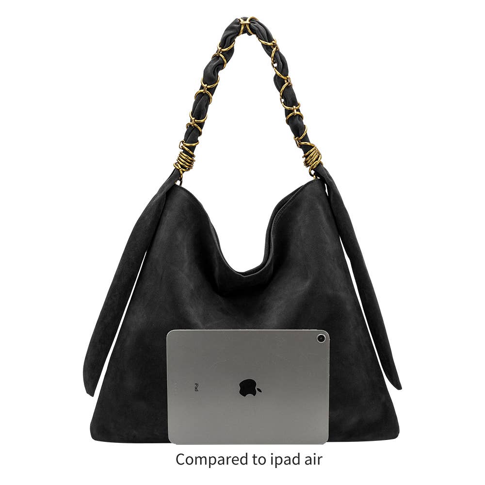 A black slouchy shoulder bag with braided black and gold handles, shown against a white background with a gray iPad Air placed inside the bag for scale and the text &