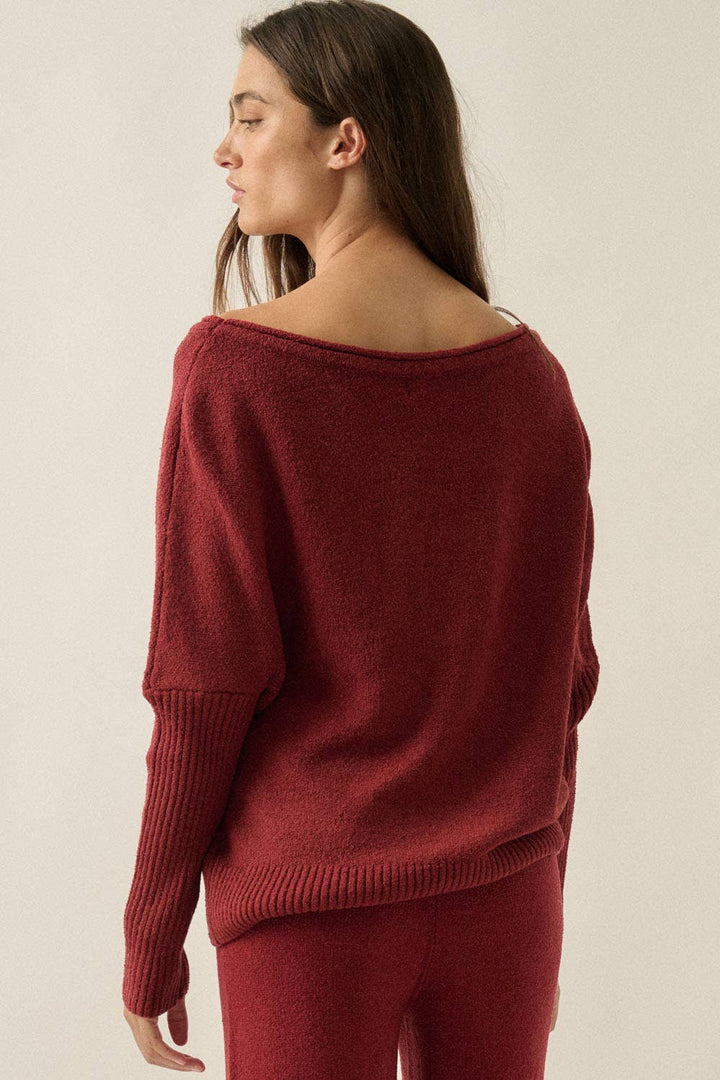 Woman wearing a burgundy knit lounge sweater against a plain background