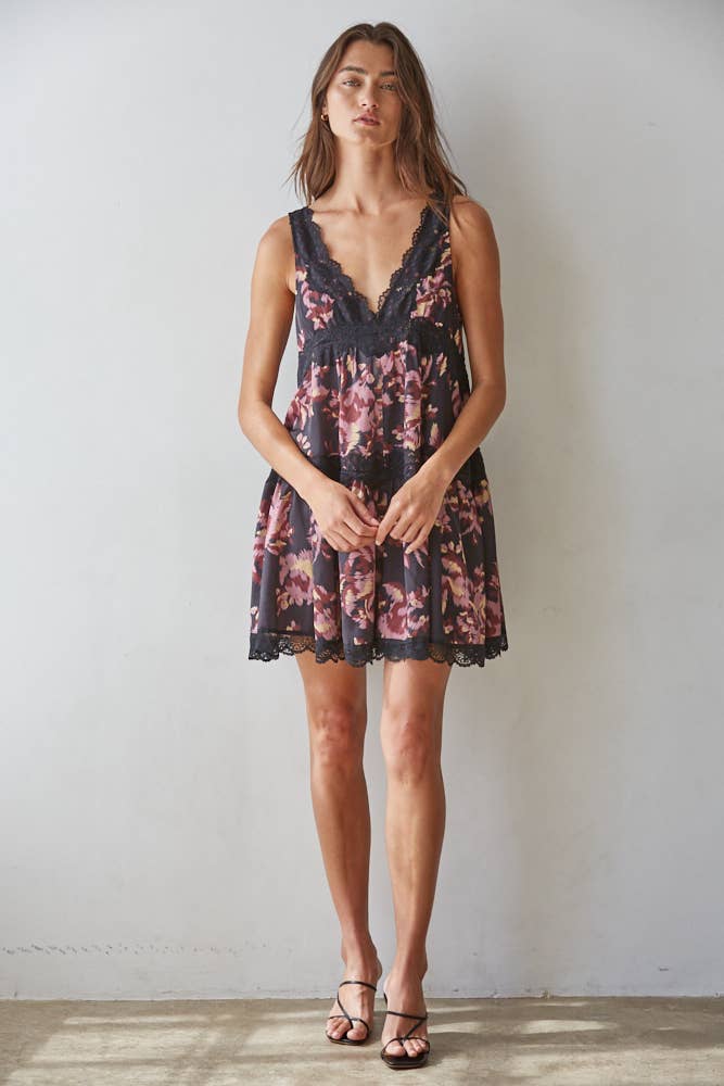 Woman wearing a floral mini dress against a plain background
