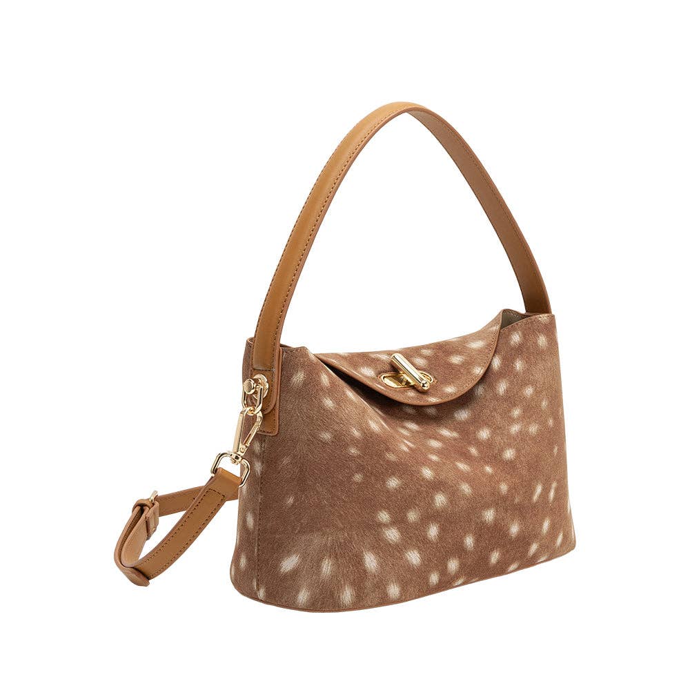 A brown shoulder bag with a white spotted animal-print pattern, featuring a tan leather handle and crossbody strap, and gold-tone hardware, set against a dark brown studio background.