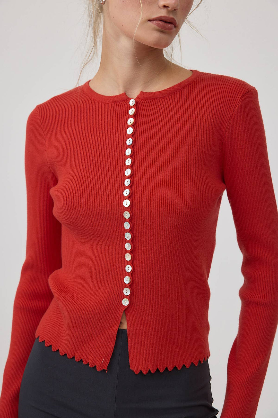 Red cardigan sweater with white buttons on a plain background