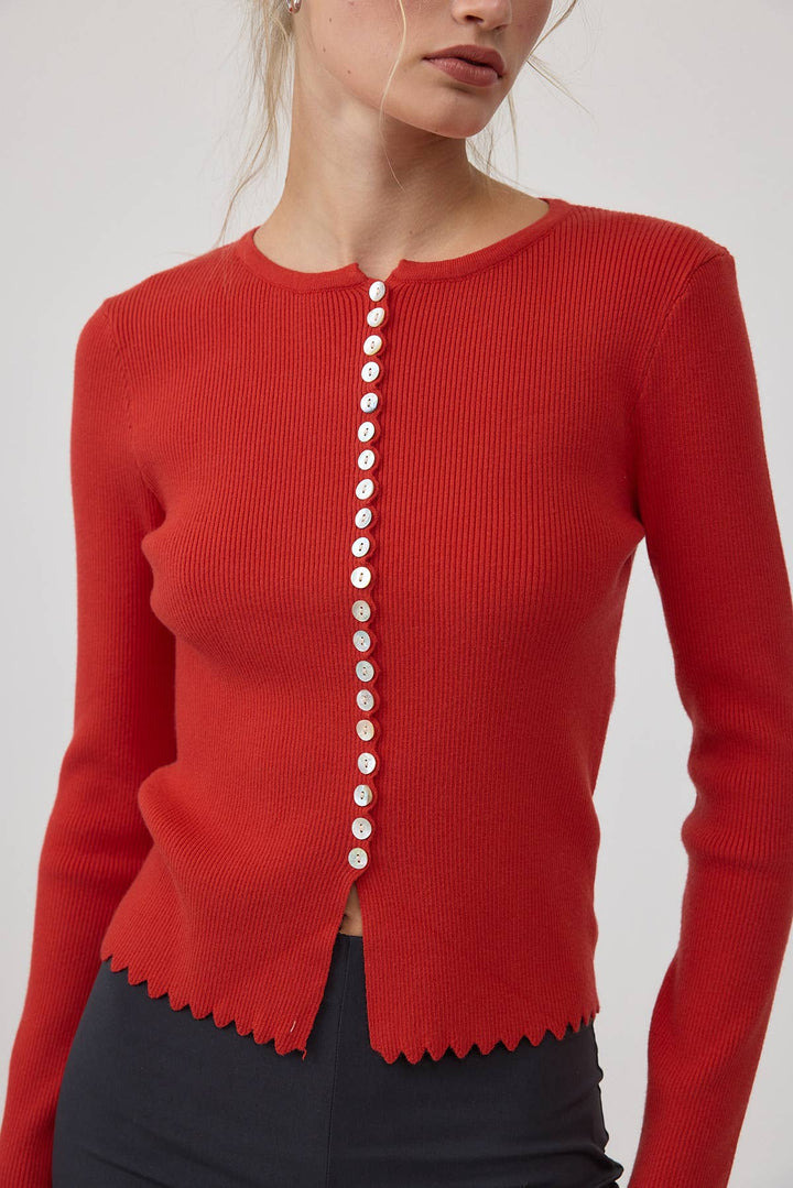 Red cardigan sweater with white buttons on a plain background