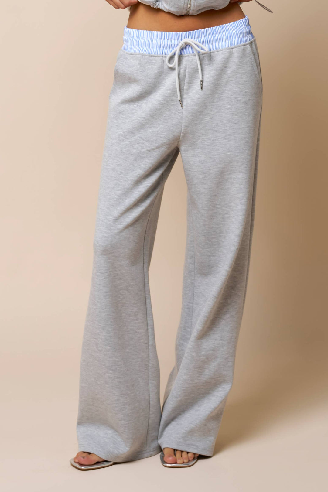 Woman's gray sweatpants with a light blue waistband on a beige background