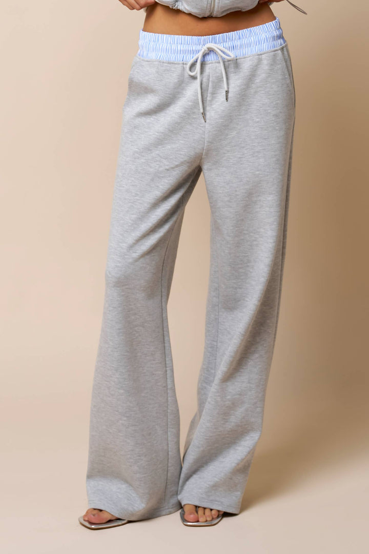 Woman's gray sweatpants with a light blue waistband on a beige background