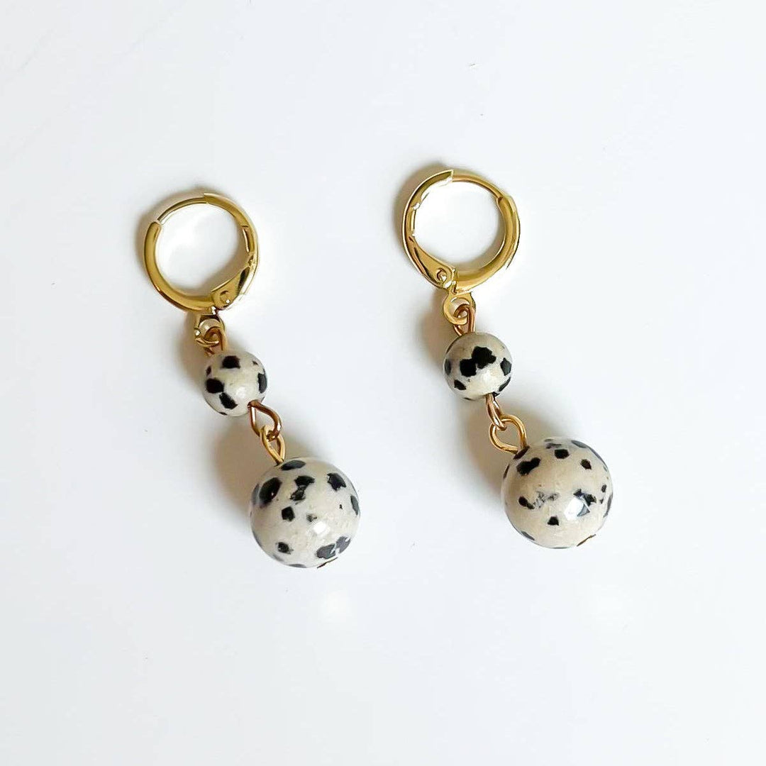 Pair of gold hoop earrings with dalmatian jasper beads on a white background