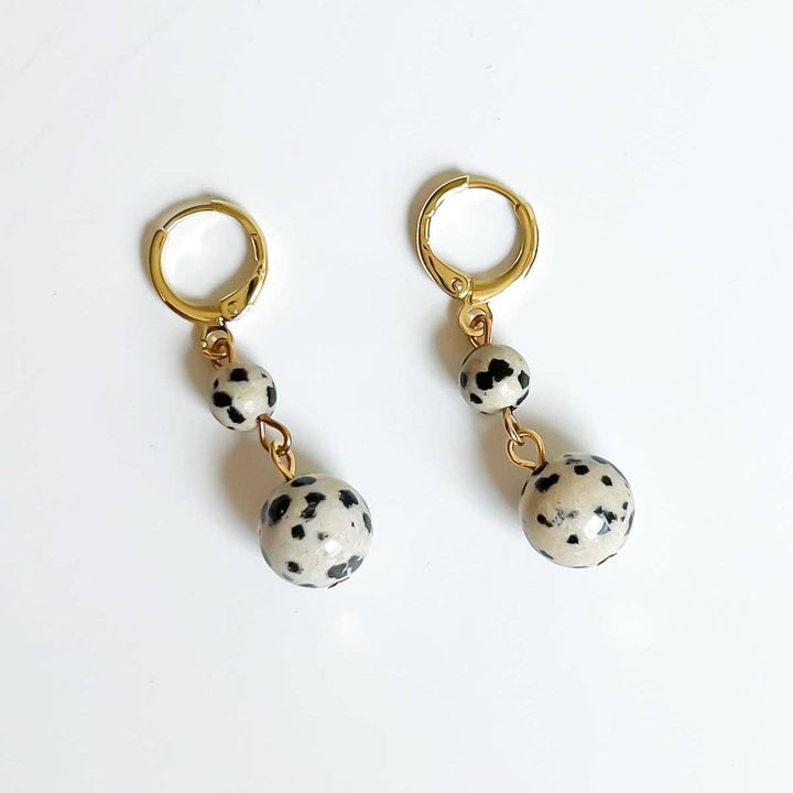 Pair of gold hoop earrings with dalmatian jasper beads on a white background
