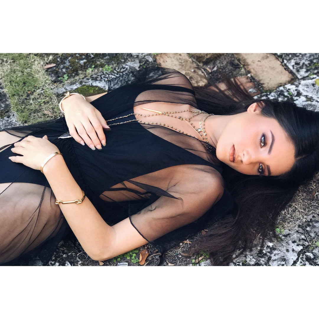 Woman lying on the ground wearing a black dress with gold bangle bracelets