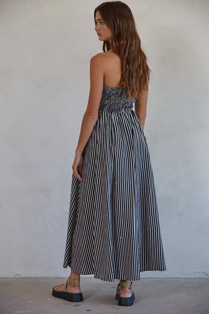 Woman wearing a navy and white striped strapless midi dress against a plain background
