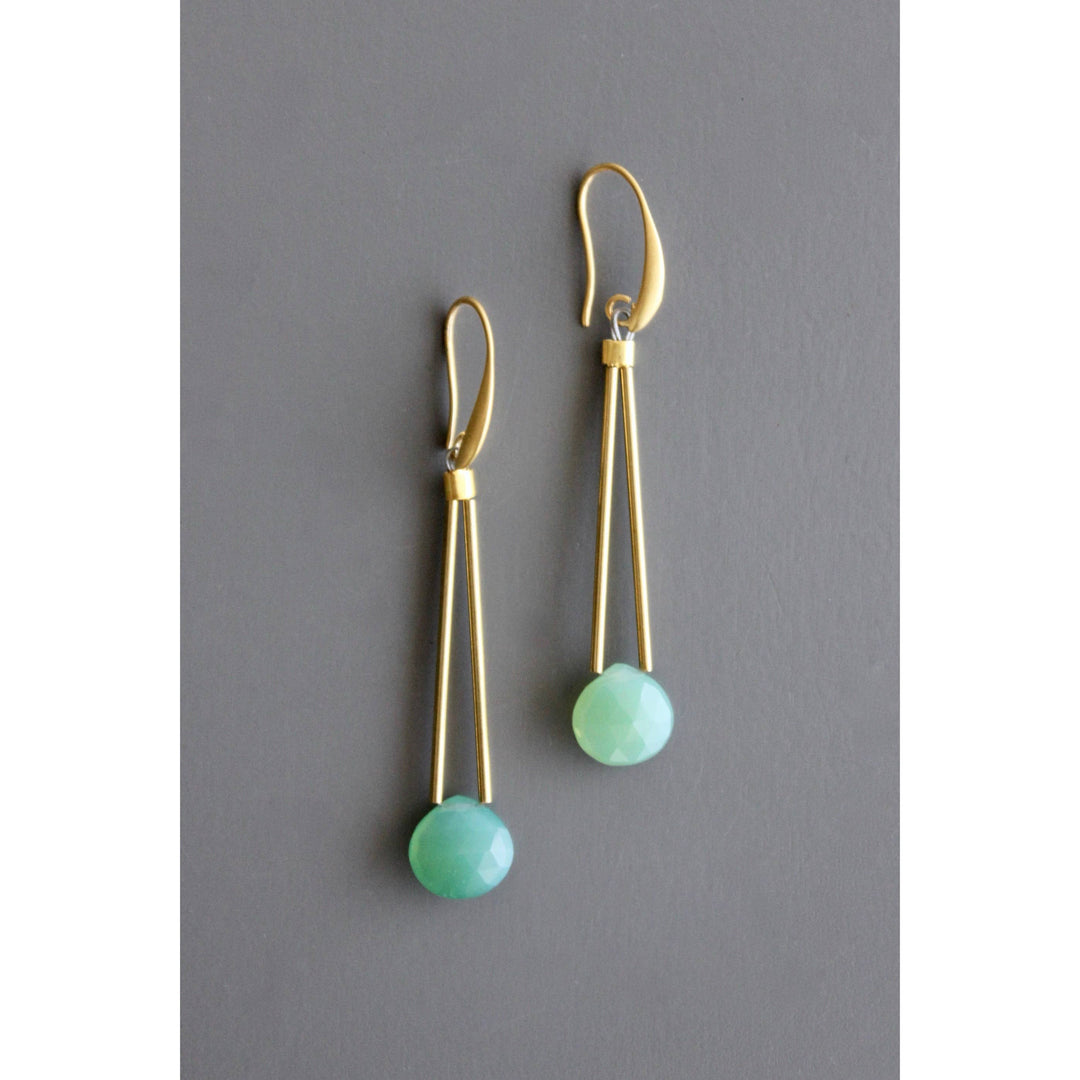 Gold dangle earrings with blue-green beads on a gray background