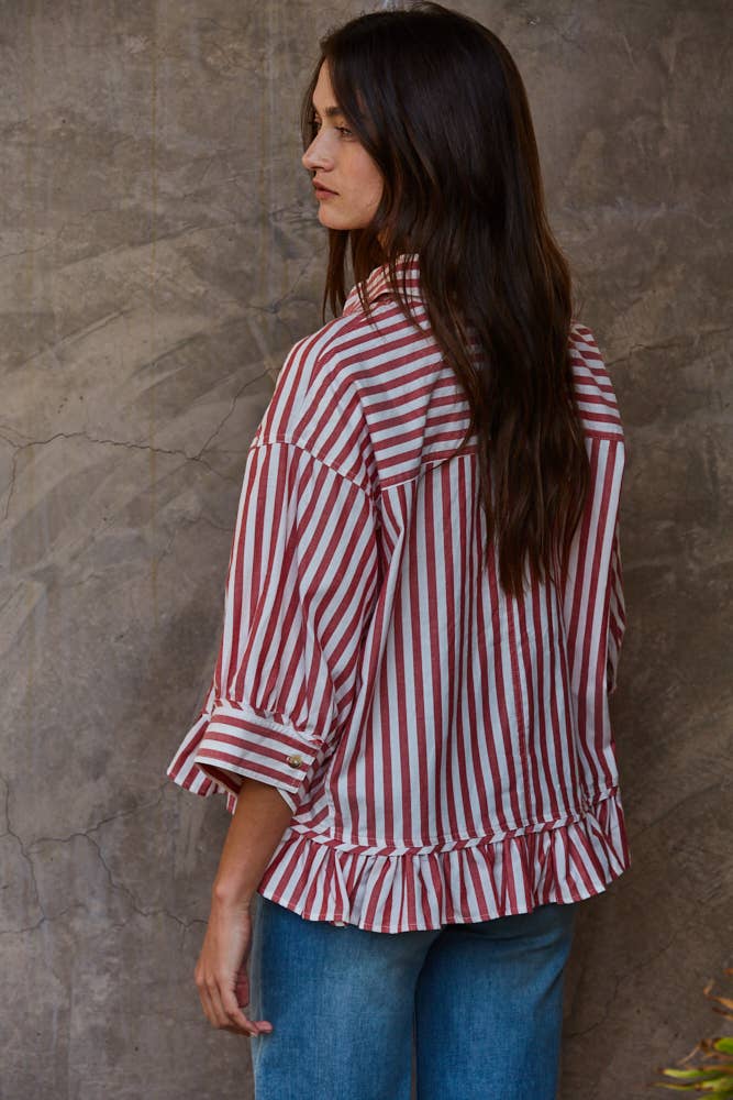Woman wearing a red and white striped shirt against a textured wall.
