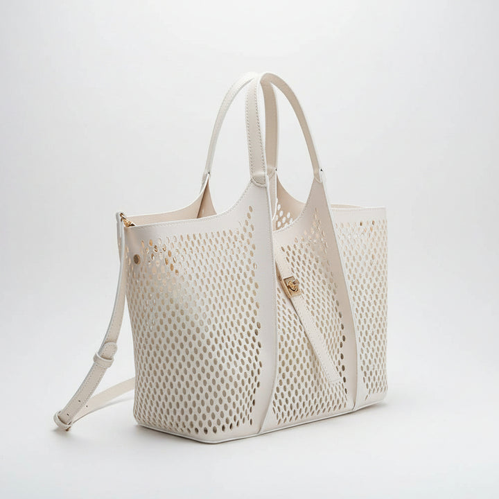 Cream colored perforated handbag with shoulder strap on a white background