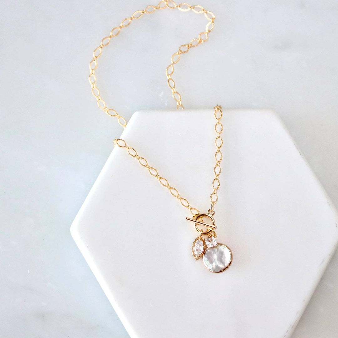 Gold necklace with a fresh water pearl pendant on a white hexagonal stand