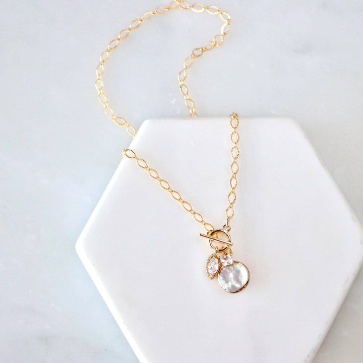 Gold necklace with a fresh water pearl pendant on a white hexagonal stand