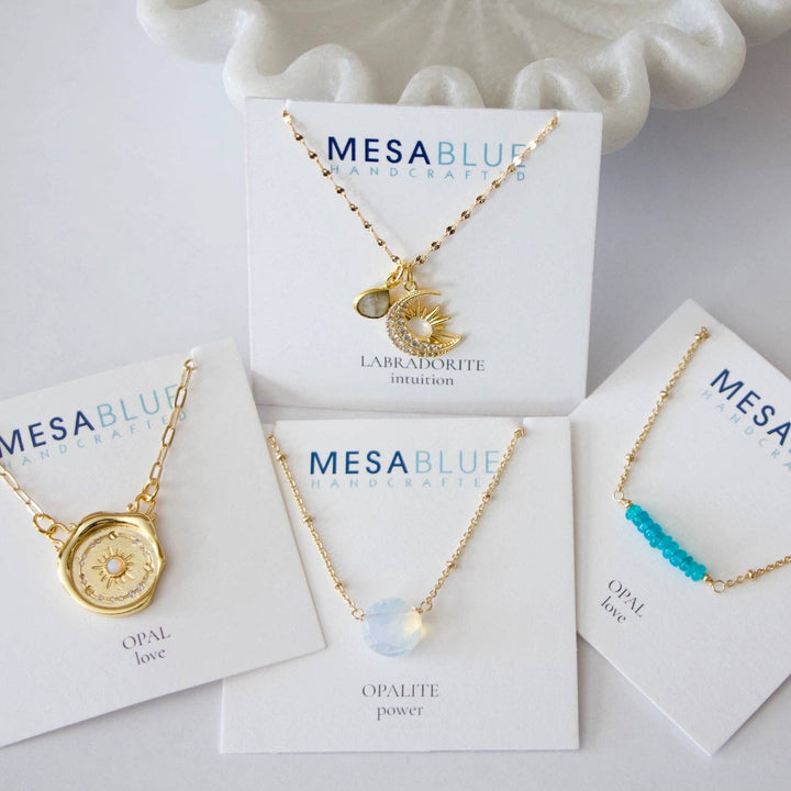 Gold necklaces on Mesa Blue branded cards with a white background