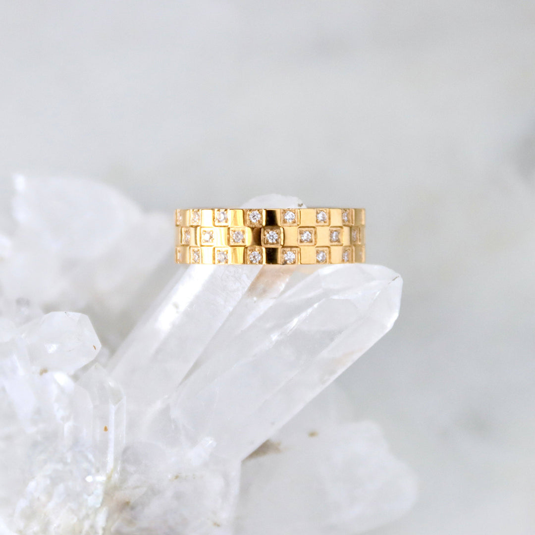 Gold chunky ring with diamonds on a white stone surface
