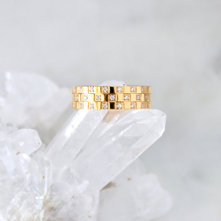 Gold chunky ring with diamonds on a white stone surface