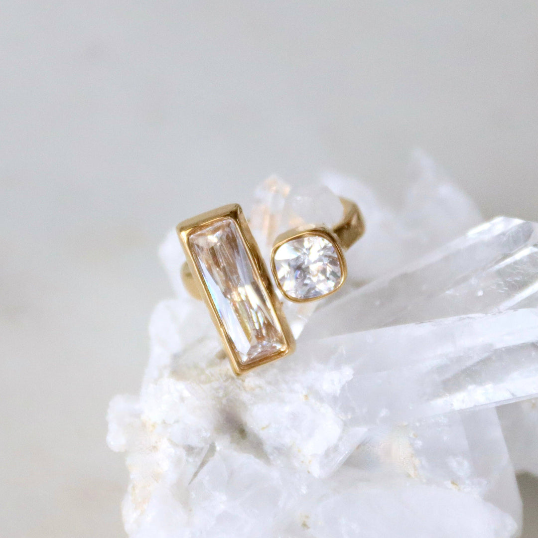 Gold costume jewelry ring with clear gemstone on a white stone surface