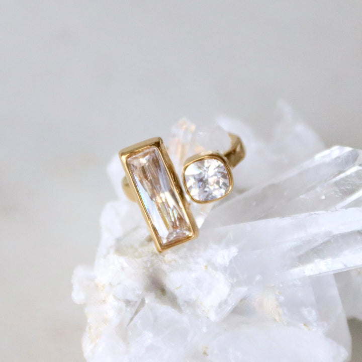 Gold costume jewelry ring with clear gemstone on a white stone surface