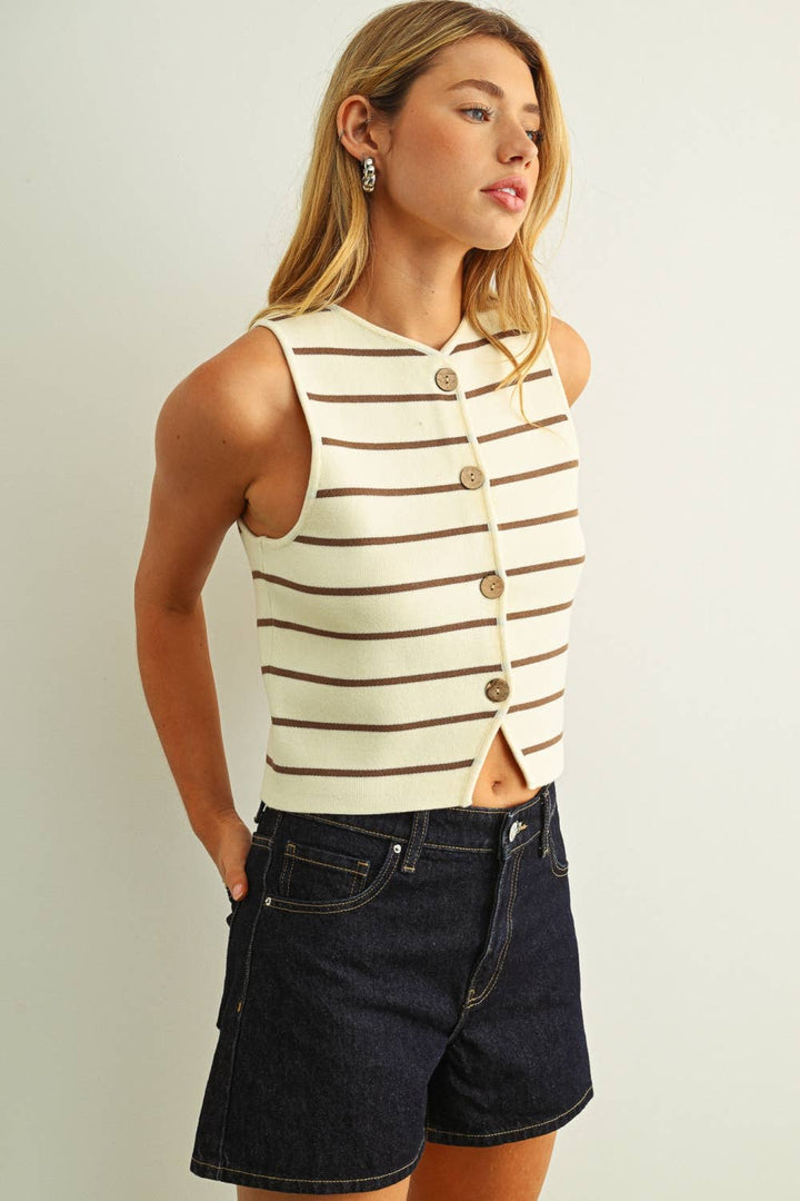 Woman wearing a striped sleeveless top and denim shorts on a plain background