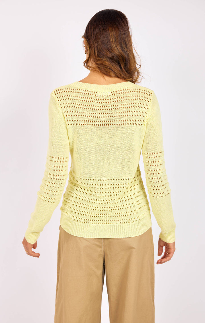 Woman wearing a light yellow crochet sweater on a white background