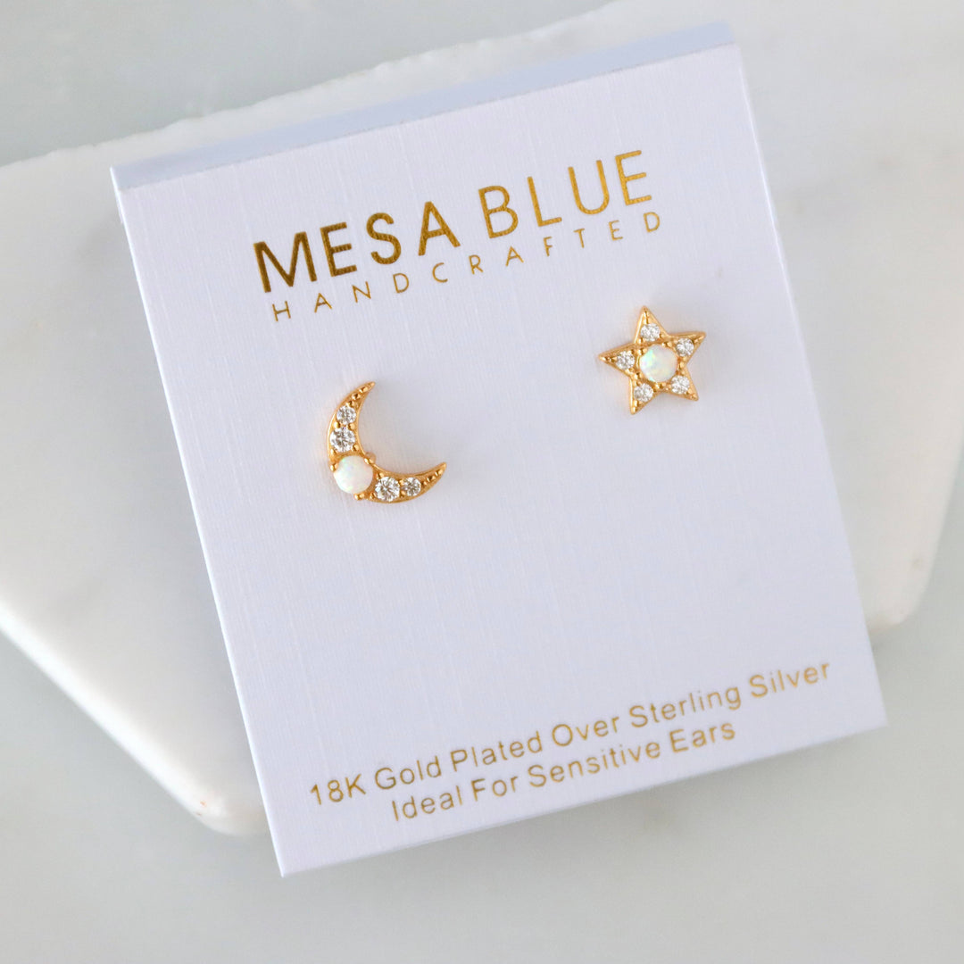Pair of gold/opal stud earrings in the shape of a moon and star on a Mesa Blue branded card.
