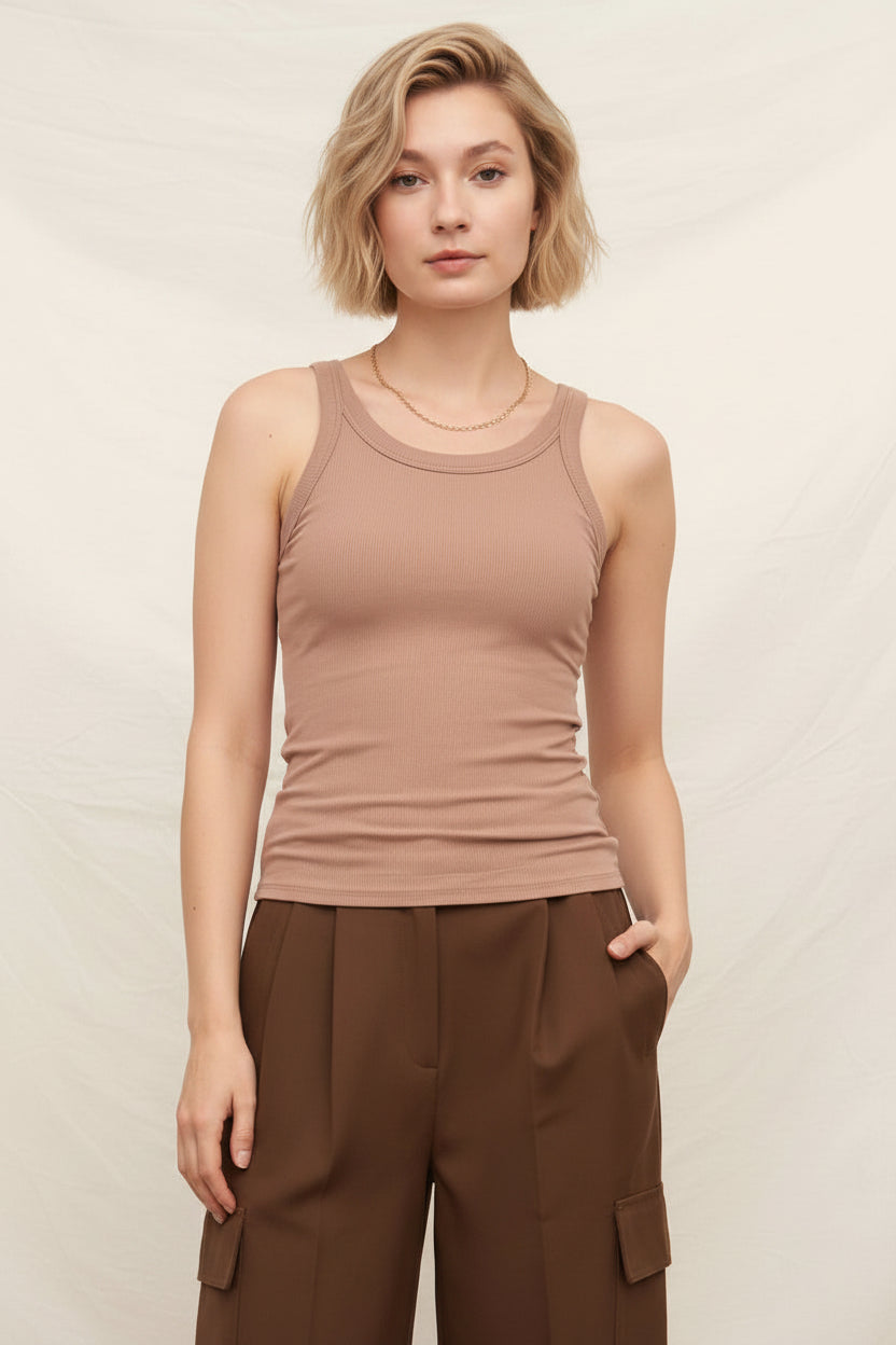 Woman wearing a brown tank top and brown pants against a beige background