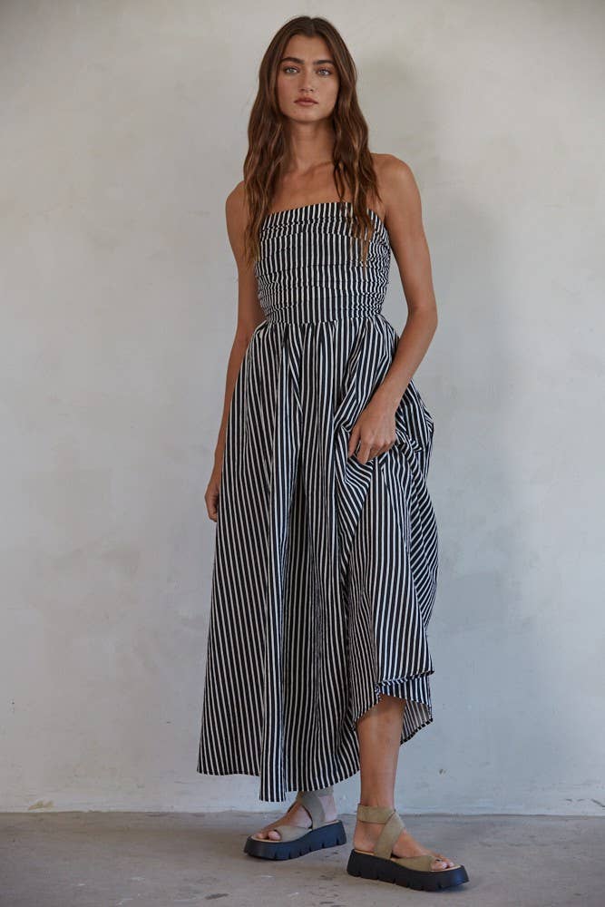 Woman wearing a navy and white striped strapless midi dress against a plain background