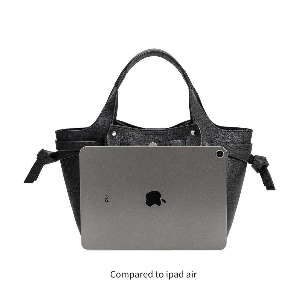 Black handbag with a laptop inside, compared to an iPad Air on a white background