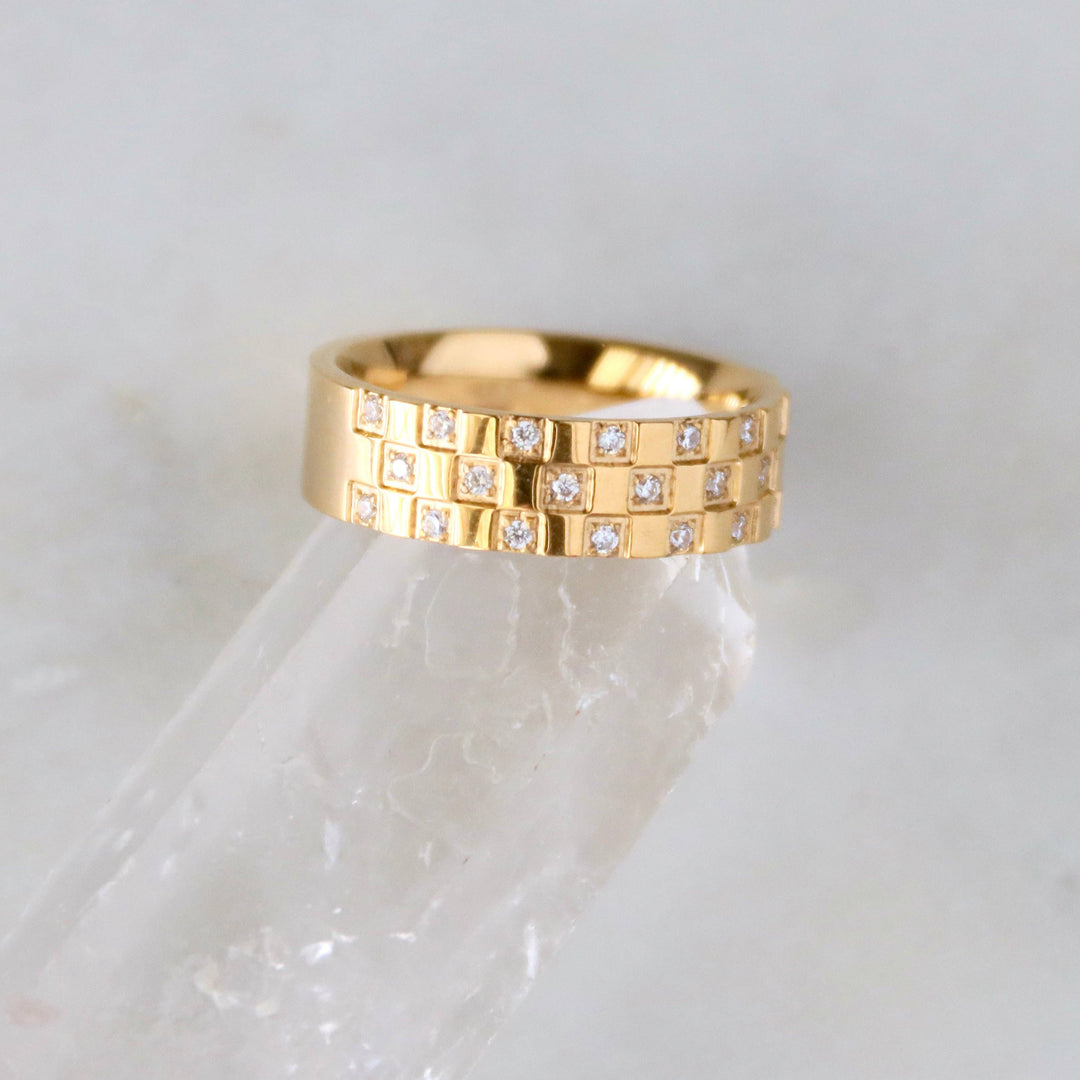 Gold ring with embedded diamonds on a white marble surface