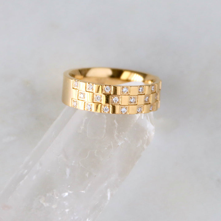 Gold ring with embedded diamonds on a white marble surface