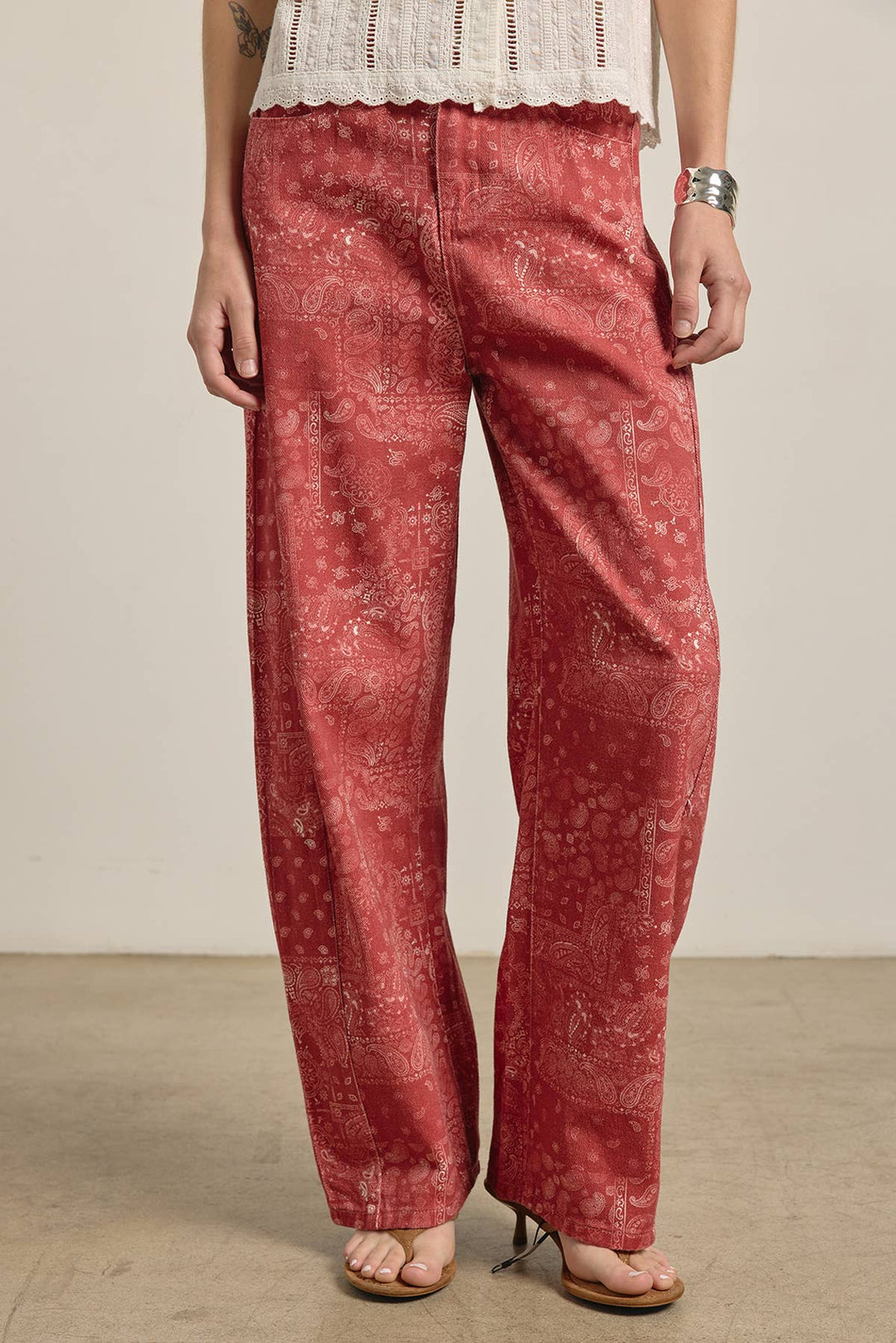 Person wearing red paisley patterned wide leg denim pants on a plain background