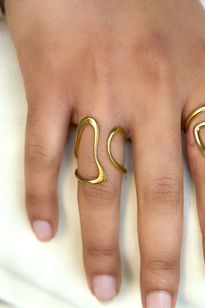 Gold adjustable ring on a finger against a neutral background