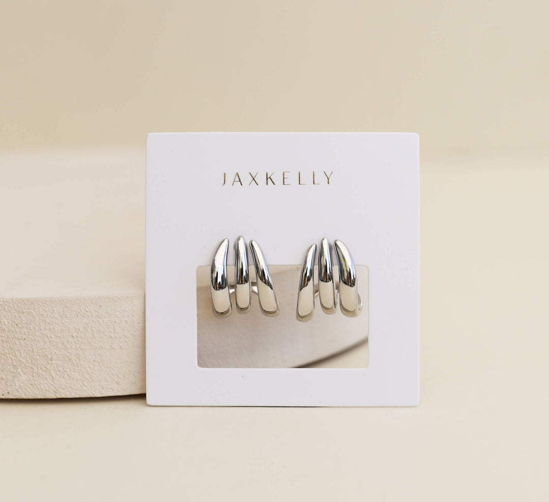 Jaxkelly silver earrings on a display card with a beige background