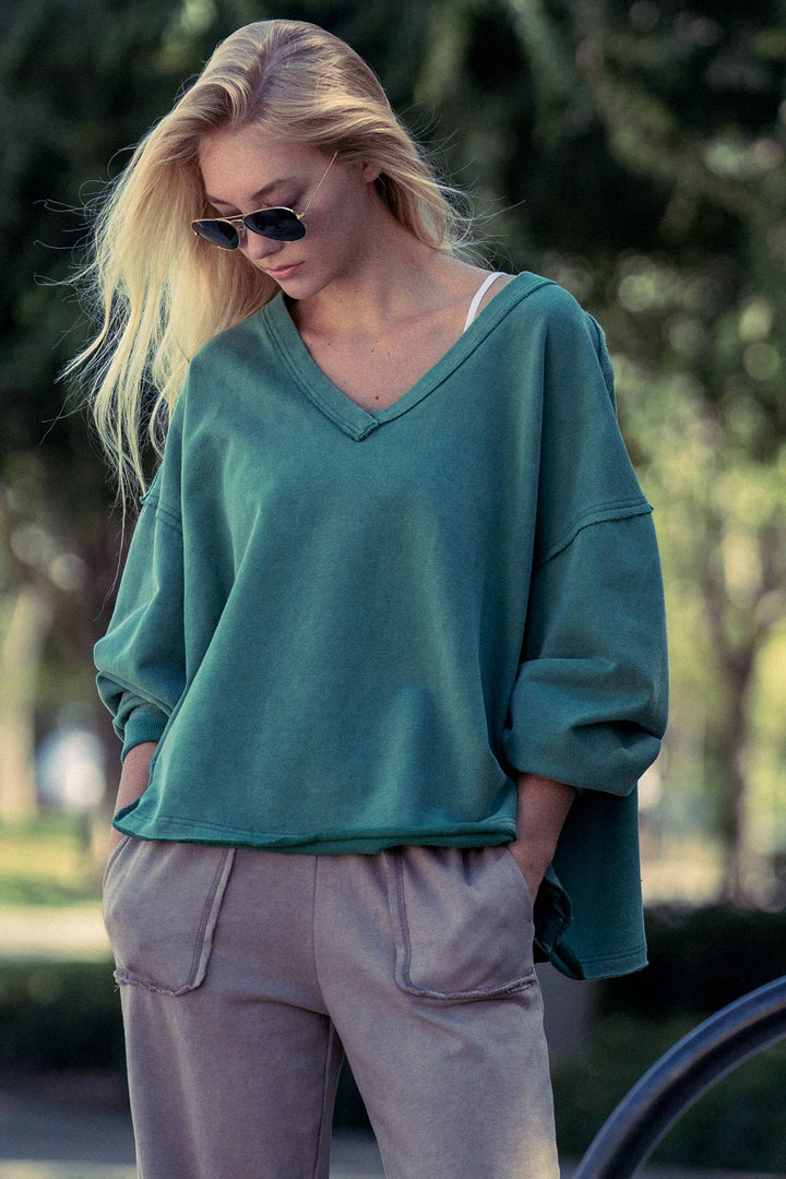 Woman wearing a teal sweater and beige pants outdoors