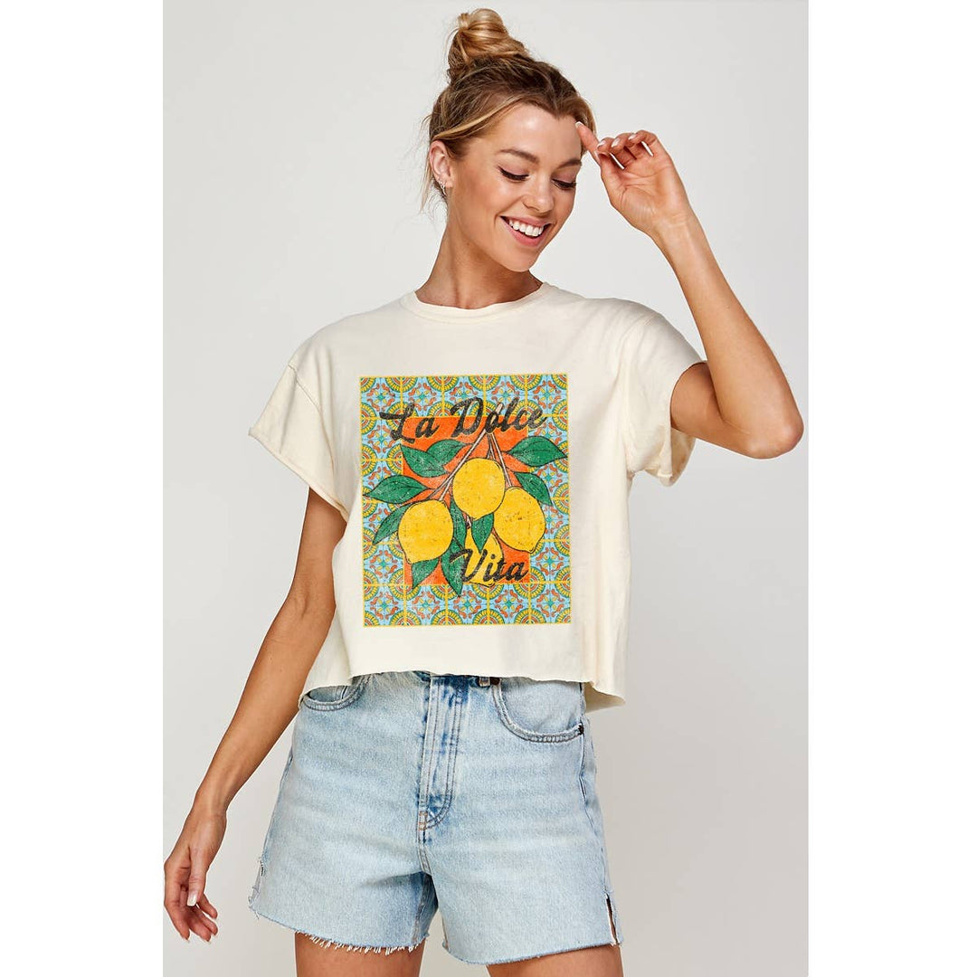Woman wearing a white t-shirt with a colorful graphic design and denim shorts on a light gray background