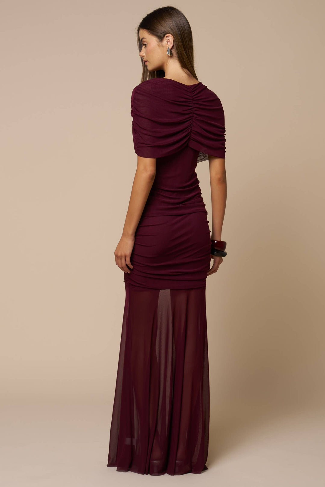 Woman wearing a formal burgundy evening gown against a beige background