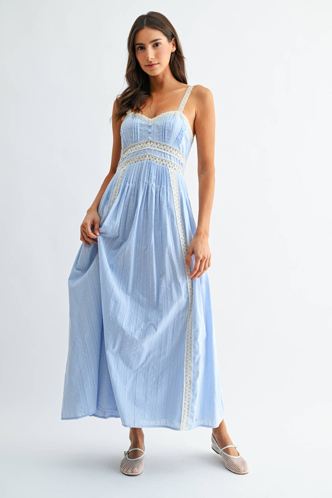 Woman wearing a light blue dress with white lace details on a white background