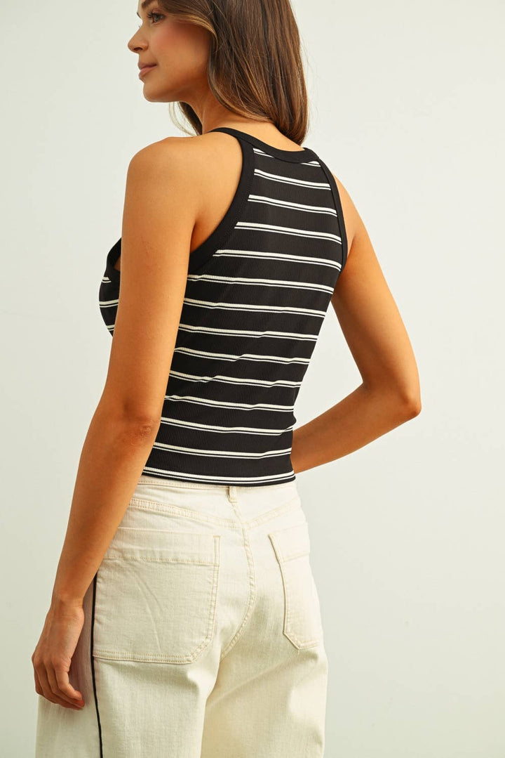 Woman wearing a black and white striped tank top against a plain background