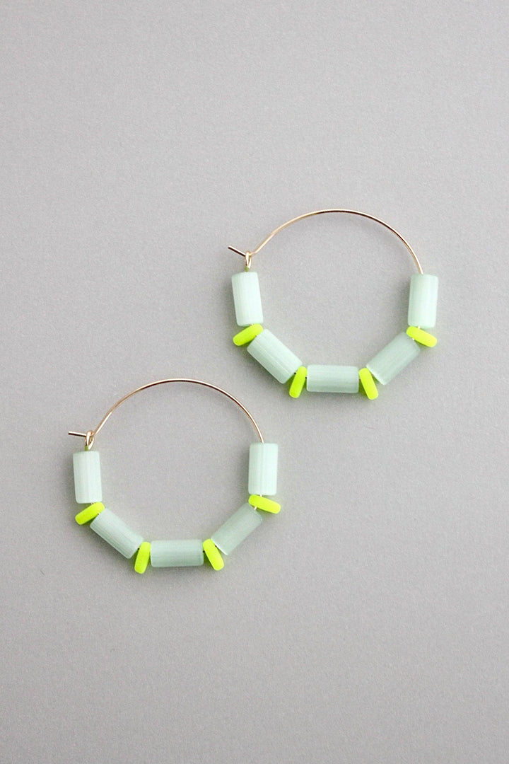 Hoop earrings with sea green cylindrical beads on a gray background