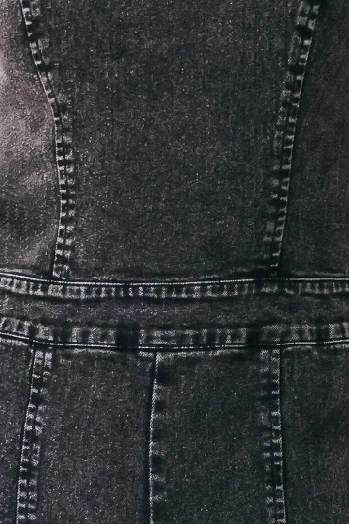 Close-up of a dark gray or black denim garment showing the fabric texture, seams, and stitching details.