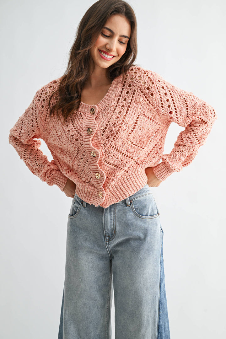 Woman wearing a pink knitted cardigan and blue jeans on a white background