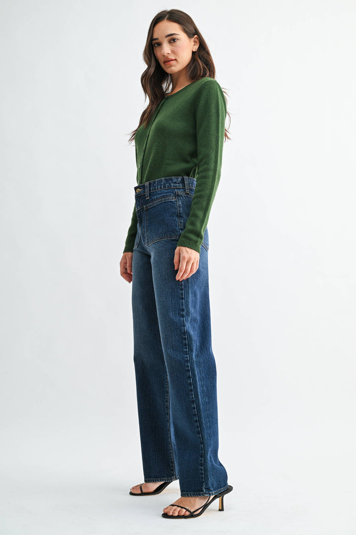 Woman wearing a green sweater and dark blue jeans on a white background