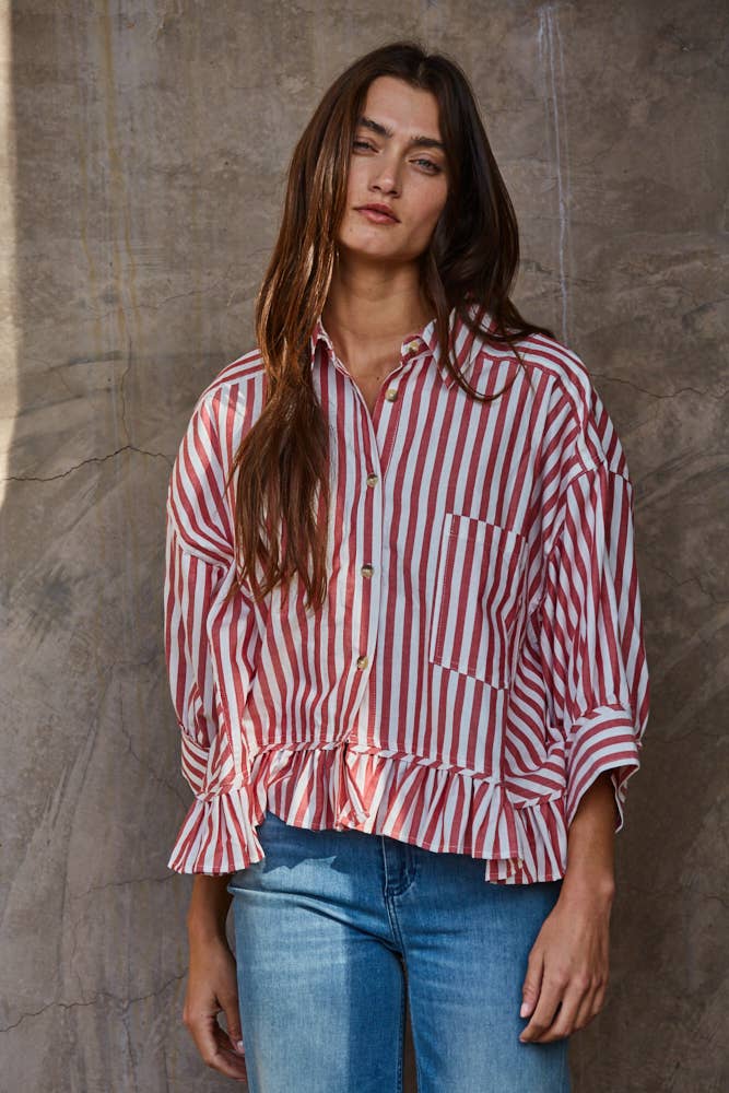 Woman wearing a red and white striped shirt against a textured wall.