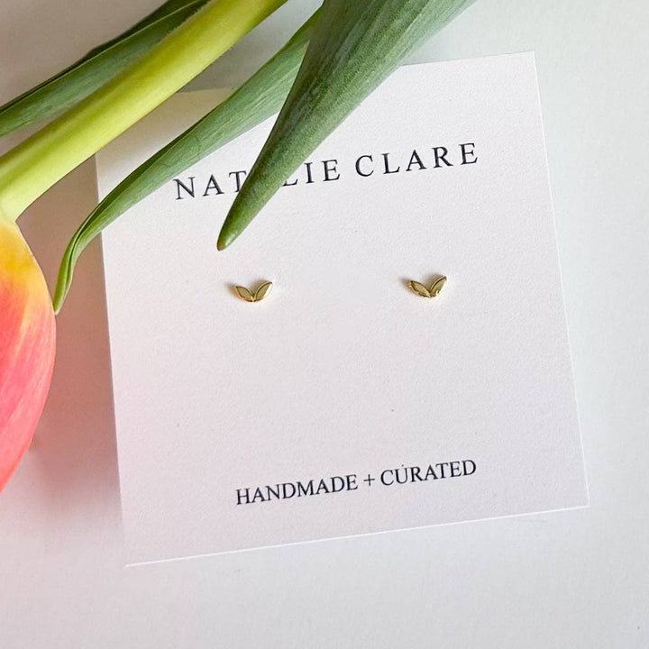 Gold earrings on a 'Natalie Clare' branded card with a tulip in the background.
